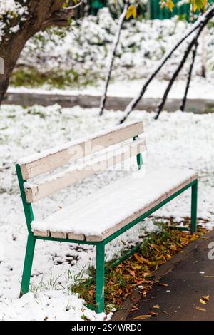 Erster Schnee auf der Bank im Stadtpark in Herbsttag Stockfoto