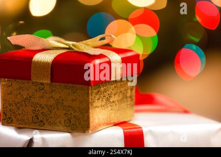 Red Christmas Box mit goldenen Band auf Grund von bunten Lichtern Stockfoto