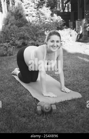 Schwarz / weiß Foto lächelnd schwangeren Frau tun Fitness auf Matte im park Stockfoto