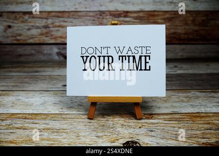 Verschwenden Sie nicht Ihre Zeit Zitat auf Papierkarte mit Staffelei auf hölzernem Hintergrund Stockfoto