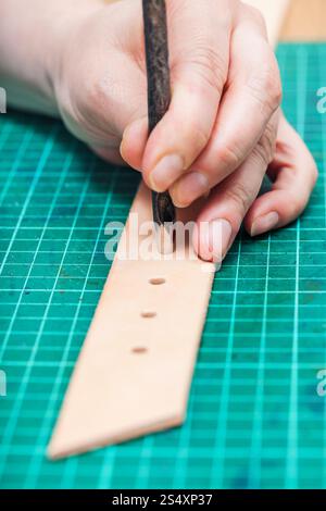 Stanzen von Löchern in Ledergürtel mit Stahl Locher auf Self-healing mat Stockfoto