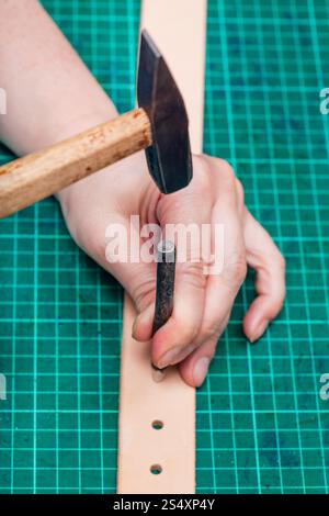 Stanzen von Löchern in Ledergürtel mit Stahl Loch Stanzen und hammer auf Self-healing mat Stockfoto