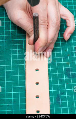 Lochung in neue Ledergürtel mit Loch Stanzen auf Self-healing mat Stockfoto