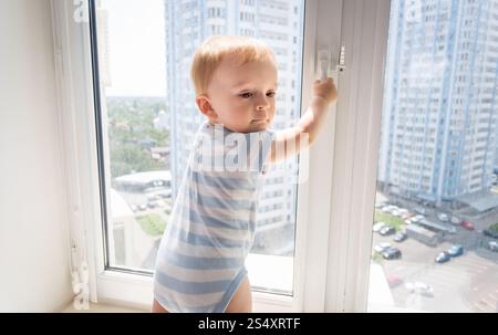 Porträt der 10 Monate alten Jungen versuchen, Fenster zu öffnen Stockfoto