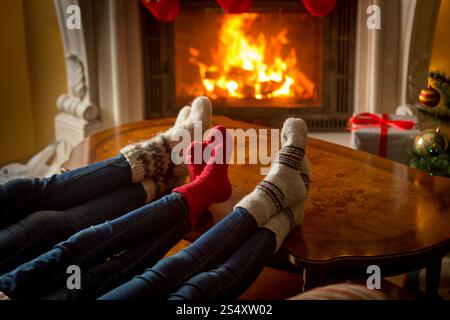 Schönes Bild von Familie Füße in Wollsocken ruht neben dem brennenden Kamin Stockfoto