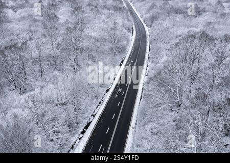 Blick aus der Vogelperspektive auf eine Bergstraße, die im Winter von Schnee befreit ist. Winterlandschaft Stockfoto