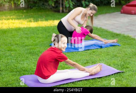 Niedliche Mädchen, die Yoga auf Gras im Garten üben Stockfoto