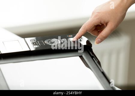 Nahaufnahme einer Geschäftsfrau, die im Büro den Knopf am Kopiergerät drückt Stockfoto