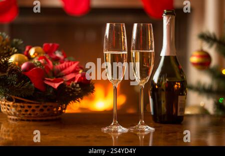 Nahaufnahme der Gläser Champagner auf dem Tisch neben der alten Uhr, die Mitternacht im Wohnzimmer zeigen, das zu Weihnachten dekoriert ist Stockfoto