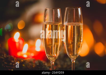 Nahaufnahme von zwei Gläsern Champagner vor brennenden Kerzen und Lichtern. Stockfoto
