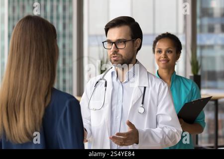 Patient stehend, zuhörend männlicher Arzt während ihres Arztbesuchs in der Klinik Stockfoto