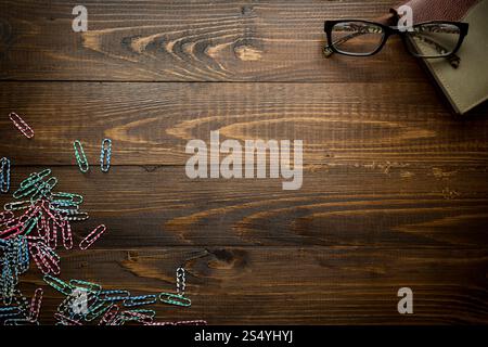 Hölzerner Hintergrund mit Notizbuch und bunten Büroklammern. Platz für Text Stockfoto