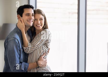 Glückliches, attraktives junges Ehepaar, das sich zu Hause umarmt Stockfoto