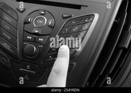 Schwarzweiß-Nahaufnahme einer Frau, die den Knopf auf dem Armaturenbrett des Autos drückt Stockfoto