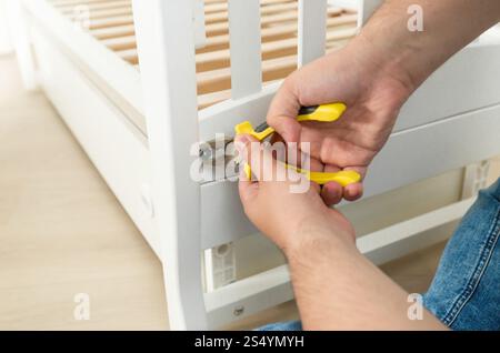 Nahaufnahme eines Mannes, der die Schrauben an Möbeln mit einem Schraubendreher festzieht Stockfoto