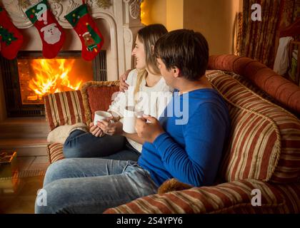 Junge Frau und Mann entspannen am Kamin und dekorierten Weihnachtsbaum Stockfoto