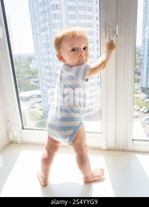 10 Monate alter Junge, der versucht, das Fenster zu öffnen Stockfoto