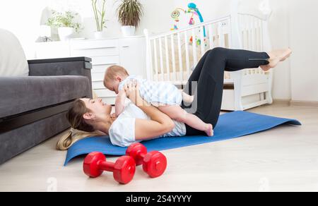 Glückliche Mutter, die zu Hause Sport macht und Spaß mit ihrem kleinen Jungen hat Stockfoto