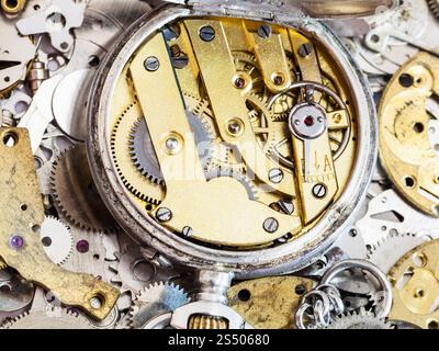 Uhrmacherwerkstatt – Öffnen Sie alte mechanische Taschenuhr aus Messing auf einem Haufen von Uhren-Ersatzteilen Stockfoto
