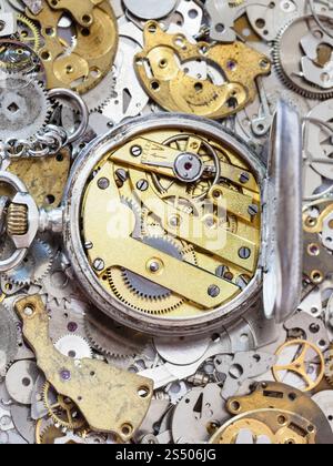 Uhrmacher Workshop - öffnen Sie alte silberne Taschenuhr mit Messing Uhrwerk auf Stapel von Uhr Ersatzteile Stockfoto