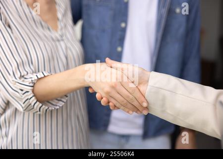 Ein paar Kunden schütteln sich die Hand mit einem Immobilienversicherer Stockfoto