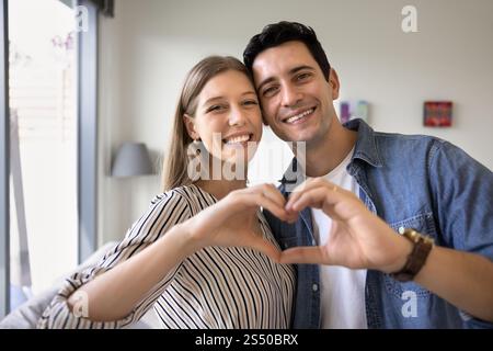 Glückliches, attraktives junges Paar, das Hand-Herz-Geste zusammen macht Stockfoto