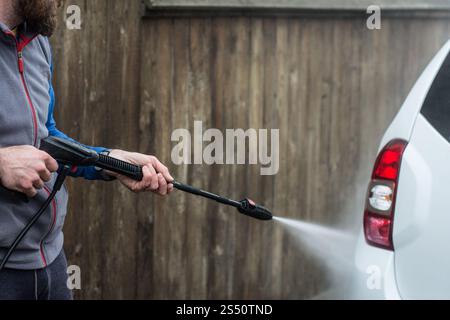 Nahaufnahme eines Mannes Hände waschen sein Auto mit einem großen Kopf Wasser von einem karcher im Freien. Reinigung und Desinfektion. Sicherheitsmaßnahmen durin Stockfoto