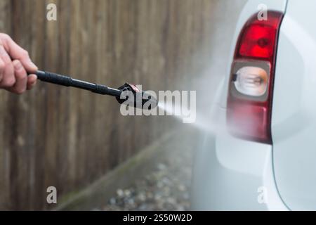 Nahaufnahme eines Mannes Hände waschen sein Auto mit einem großen Kopf Wasser von einem karcher im Freien. Reinigung und Desinfektion. Sicherheitsmaßnahmen durin Stockfoto