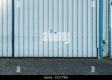 Das Schild „kein Parken“ ist auf ein gewelltes Metallgaragentor gestempelt Stockfoto