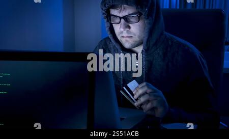 Porträt eines jungen männlichen Hackers, der Programmcode für den Diebstahl von Kreditkarten schreibt. Porträt eines männlichen Hackers, der Programmcode für Diebstahl schreibt Stockfoto