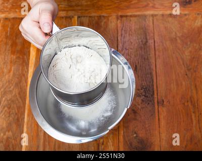 Zubereitung der Torte - Sichten das Mehl durch Sichter in Edelstahl Stockfoto