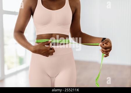 Nahaufnahme der sportlichen Frau, die Taille mit Band misst. Schlankheitskonzept Stockfoto