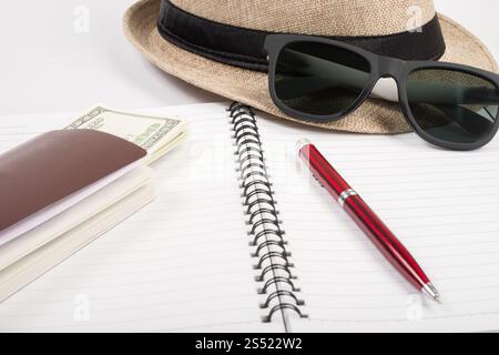 Pässe, Hut, Kamera, Brille, Stift auf einem Papierboden bereit zum tr. Pässe, Hut, Kamera, Brille, Stift auf einem Papierboden bereit für die Reise. Stockfoto