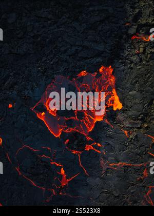 Nahaufnahme der glühenden Lava-Risse und des gekühlten vulkanischen Gesteins, die die Rohtexturen der geothermischen Aktivität in Island zeigen Stockfoto