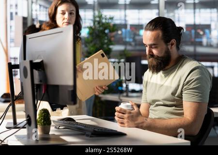 Müder Mitarbeiter des Unternehmens, der beim Recherchen für ein Teamprojekt vom Manager am Schreibtisch im Büro einschlafen musste. Erschöpfter Mann, der vor dem Computerbildschirm am Arbeitsplatz schläft, vom Teamleiter erwischt Stockfoto