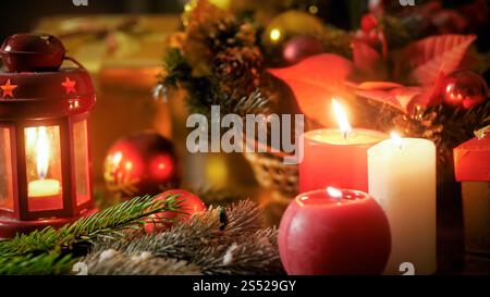 Nahaufnahme von brennenden Kerzen und Weihnachtsdekorationen auf Holztisch. Perfekte Kulisse für Winterferien und Feiern. Nahaufnahme von Stockfoto
