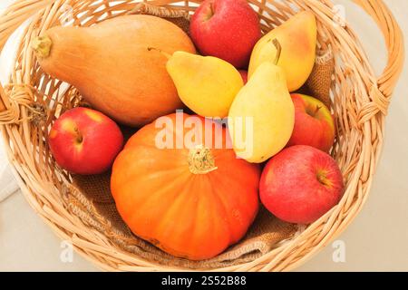 Äpfel, Birnen und Kürbisse in einem Strohkorb. Orange reife Früchte. Birnen, Äpfel und Kürbisse sind eine beliebte Zutat beim Kochen. Draufsicht. Stockfoto