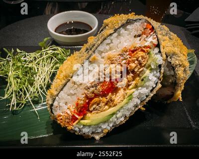 Sushi-Burger mit Lachs, Avocado, Salat und Reis in Nahaufnahme auf einem Teller Stockfoto
