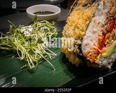 Sushi-Burger mit Lachs, Avocado, Salat und Reis in Nahaufnahme auf einem Teller Stockfoto