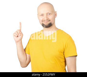 Ein kahler Mann mit kurzem Bart, der ein gelbes T-Shirt trägt, posiert vor weißem Hintergrund. Stockfoto