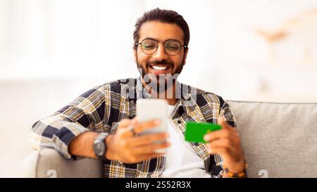 Fröhlicher arabischer Mann mit Kreditkarte und Handy Stockfoto