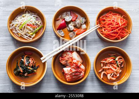 Die koreanische Küche - essstäbchen auf Schüsseln mit verschiedenen Beilagen (Banchan oder panchan) auf Graue Tabelle Stockfoto