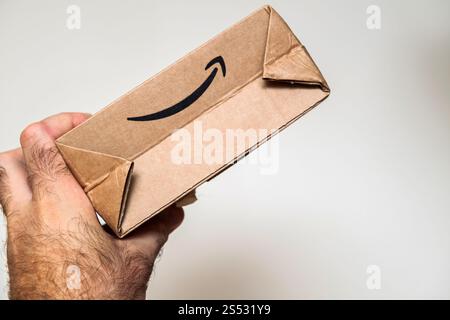 Paris, Frankreich - 22. September 2021: Eine Hand, die einen kleinen Karton mit dem Amazon Smile-Logo greift, das vor einem neutralen Hintergrund in der Nähe angezeigt wird Stockfoto