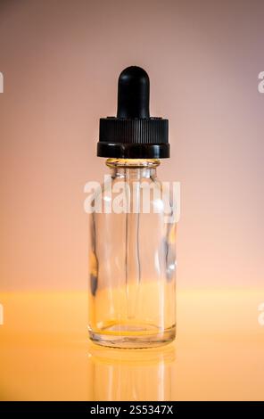 Tropfflasche aus Glas und Pipette auf orangem Hintergrund. Tropfflasche aus Glas auf orangem Hintergrund Stockfoto