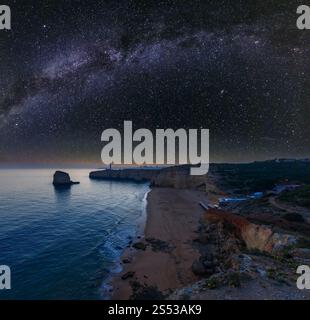 Küste bei Nacht mit Leuchtturm von Ponta do Altar und starry Milchstraße am Himmel. Blick nach Westen über Praia da afurada Strand (Ferragudo, Lagoa, Algarve, Stockfoto