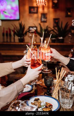 Feiern Sie mit Aperol Spritz Toast, gemütliche Dinner Party Atmosphäre in einem stilvollen Restaurant Ambiente Stockfoto
