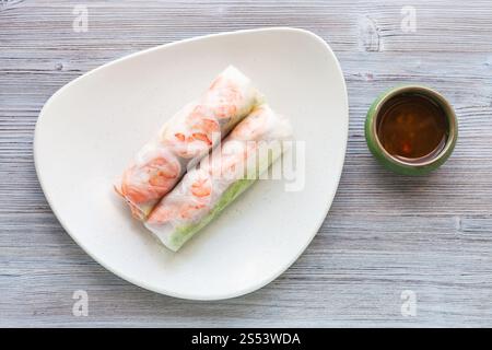 Ansicht von oben serviert Nem Cuon (frisch Vietnamesisch nem Rolle mit Garnelen, Mango und Ingwer) auf die weiße Platte auf hölzernen Tisch Stockfoto