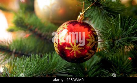 Nahaufnahme eines roten funkelnden Kugels auf einem wunderschönen Weihnachtsbaum. Perfekter abstrakter Hintergrund für Winterferien oder Feierlichkeiten. Nahaufnahme von Stockfoto