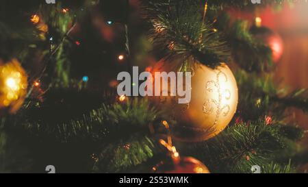 Nahaufnahme-Bild von leuchtenden Lichtern und bunten Kugeln auf dem Weihnachtsbaum im Haus. Perfekter Hintergrund für Winterferien und Feierlichkeiten. Nahaufnahme Stockfoto