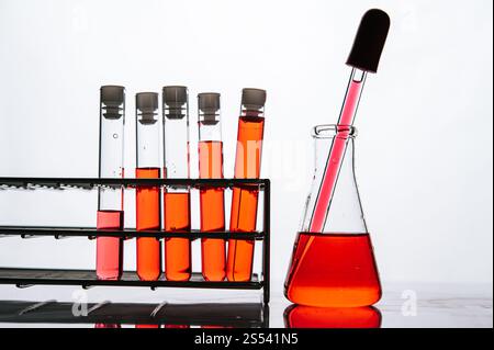 Orangene Chemikalien in einer wissenschaftlichen Glasröhre auf einem Regal. Stockfoto